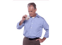 a man in a blue shirt is drinking a glass of milk