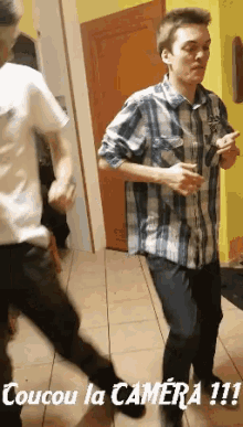 a man in a plaid shirt is dancing with the words coucou la camera !!! above him