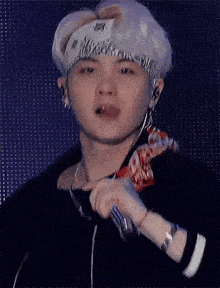 a young man wearing a bandana is holding a microphone and sticking his tongue out .