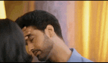 a man is kissing a woman on the forehead in a close up .