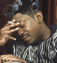 a man smoking a cigarette while wearing a black and white shirt
