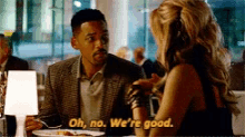 a man and a woman are sitting at a table and the man is saying oh no we 're good