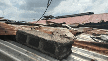 a concrete block is laying on top of a rusty metal roof