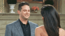 a man in a suit and a woman in a dress are standing next to each other in front of a fireplace .