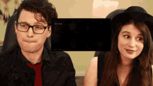 a man and a woman are sitting in front of a screen that says resume game