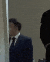 a man in a suit and tie is standing in front of a mirror .
