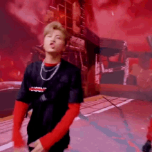 a man wearing a black shirt and red sleeves is dancing on a stage .