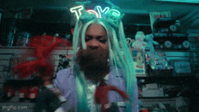 a woman with dreadlocks and a neon sign that says toy