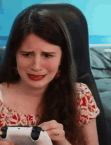 a woman is playing a video game with a controller and making a funny face