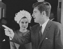 a man and a woman are standing next to each other and the woman is pointing