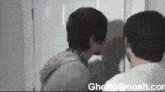 two men are looking at themselves in a mirror with the website ghettosmash.com in the lower right corner