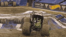 a monster truck is on a muddy track in front of a great clips sign