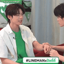 a man in a green shirt is shaking another man 's hand