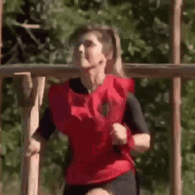 a woman in a red vest is running on a wooden fence .