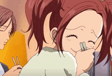 a girl with red hair is holding chopsticks in her hand