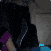 a little girl in a purple shirt is sitting in a black car seat