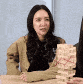 a woman is sitting at a table with a stack of jenga blocks on it