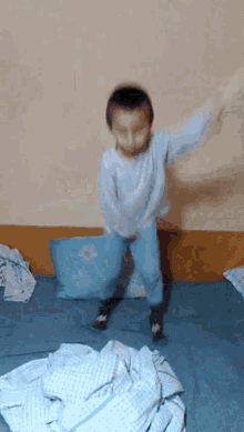 a young boy is jumping on a bed with a pillow