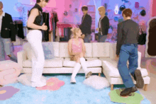 a woman in a pink dress is sitting on a couch surrounded by people
