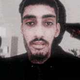 a close up of a man 's face with a beard and black shirt