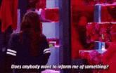 a woman is standing in front of a display of red flowers and asking does anybody want to inform me of something ?