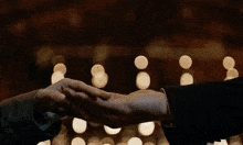 a man and a woman are holding hands in front of a wall of lights