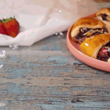 a strawberry sits on a napkin next to a plate of pastries