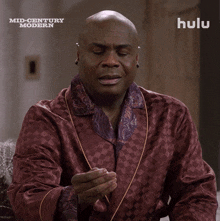 a man in a burgundy robe is sitting in front of a sign that says hulu