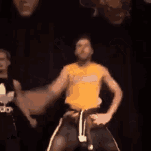 a man in a yellow shirt and black pants is dancing