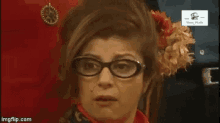 a woman wearing glasses has a flower in her hair and a sign that says share media on it