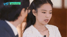 a woman in a white dress is talking to a man in a suit on a tv show .