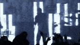 a silhouette of a man standing in front of a crowd with their hands in the air