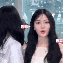 a woman with long black hair is looking at the camera with a sign in the background that says ' 방국 '