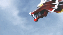 a red and white dragon with sharp teeth is flying in the air