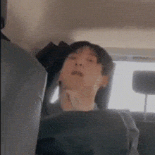a person is sitting in the back seat of a car with their head down .