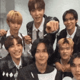a group of young men are posing for a picture while one of them is pointing at the camera .