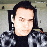 a man in a plaid shirt is taking a selfie with pixverse.ai in the background