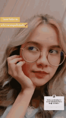a woman wearing glasses and a blue shirt has a message in a foreign language