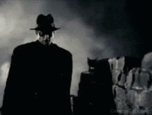 a man in a fedora is standing in front of a brick wall .