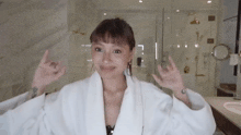 a woman in a bathrobe is making a devil horn sign