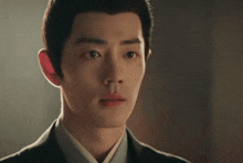 a close up of a young man in a suit and tie looking at the camera .