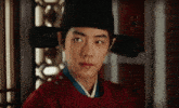 a man wearing a black hat and a red kimono