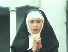 a nun is holding a rosary in her hands and praying .