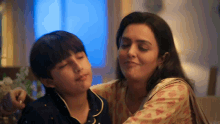 a woman is petting a young boy on the cheek