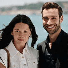 a man and a woman standing next to each other smiling for the camera