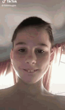 a young boy with a missing tooth is smiling for a tiktok video