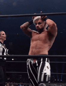 a man in a wrestling ring with a referee behind him that says ' aew ' on it