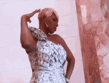 a woman in a dress made out of dollar bills is standing in front of a pink wall .