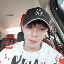 a young man wearing a ny hat and a white shirt is sitting in a car