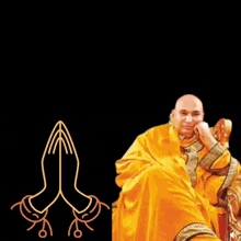 a bald man in a yellow robe is sitting in a chair with his hands folded in prayer .